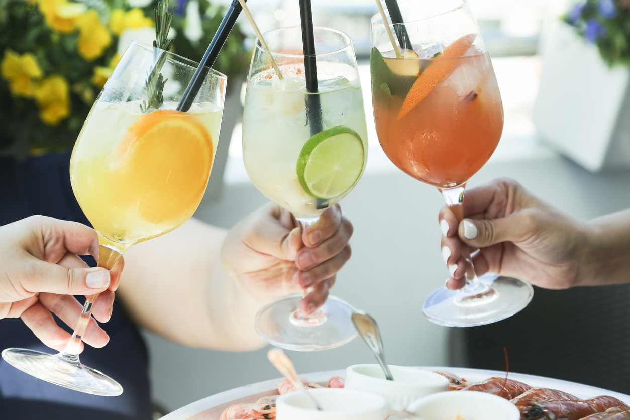 Hands with colorful best mixers for vodka in glasses