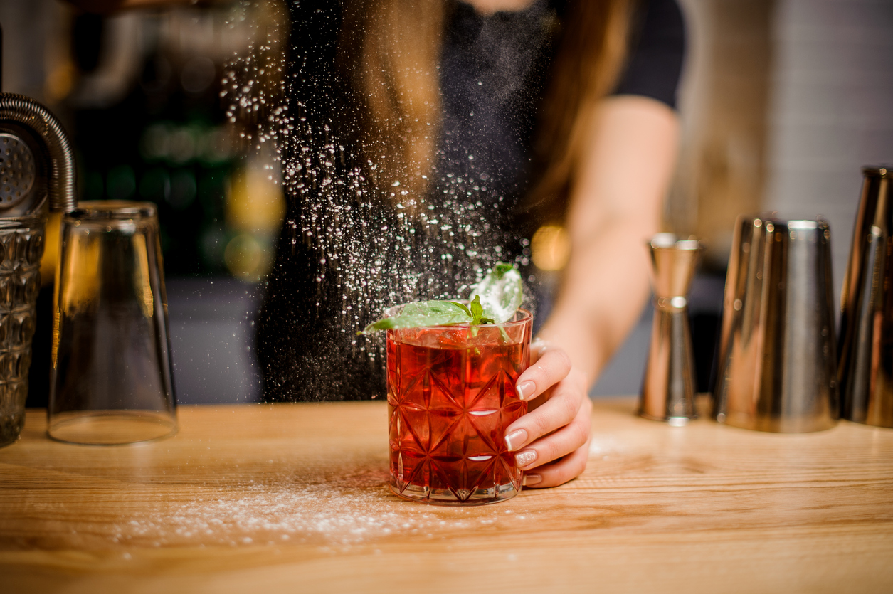 Woman using beverage tools at home bar to make cocktail
