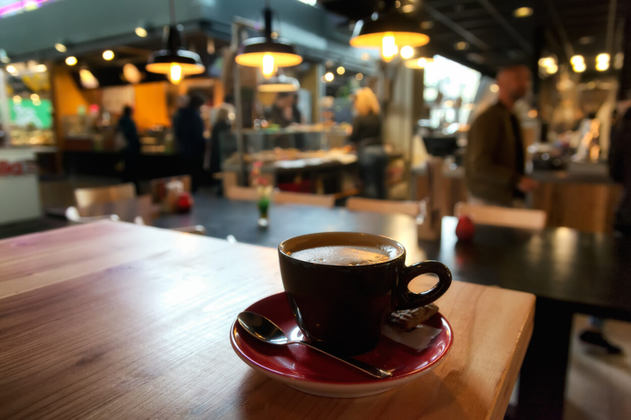 A cappucino sits on a table in a modern coffee shop that clearly follows 2020 coffee trends.