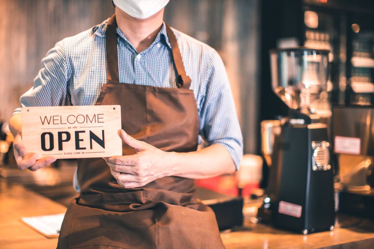 Stock image of a person holding Welcome open board